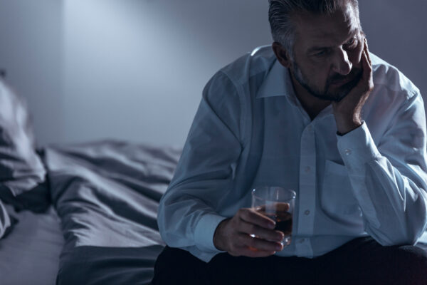 Close-up of a man with midlife crisis sitting on a bed with one